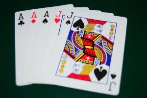 Ilustracija full house poker kombinacije: tri iste karte i jedan par poređani na zelenom stolu uz poker žetone.