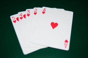 Ilustracija straight flush kombinacije u pokeru: pet uzastopnih karata iste boje poređanih na zelenom stolu uz poker žetone.
